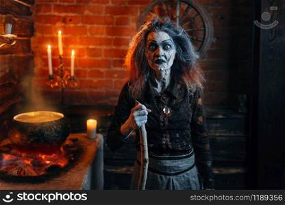 Scary witch on spiritual seance, cooking, witchcraft with candles. Female foreteller calls the spirits, terrible future teller. Scary witch on spiritual seance, cooking