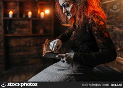 Scary witch reads spellbook, dark powers of witchcraft, spiritual seance. Female foreteller calls the spirits, terrible future teller. Scary witch reads spellbook, spiritual seance