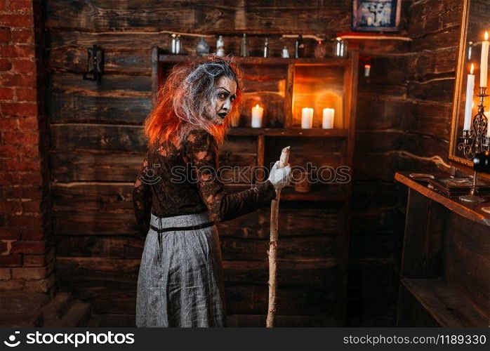 Scary witch with a cane, back view. Spiritual seance of dark magic. Female foreteller calls the spirits, terrible fortune teller