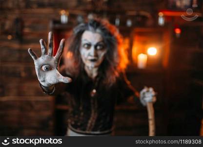 Scary witch with an eye in the palm reads mystic spell, spiritual seance. Female foreteller calls the spirits, terrible fortune teller