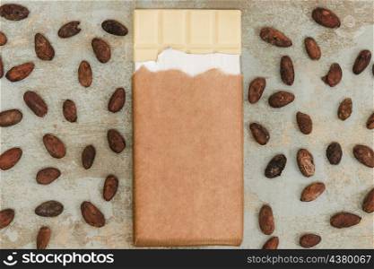 scattered cocoa beans with white chocolate bar grunge background