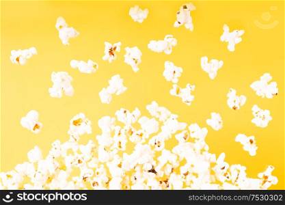 Scattered fresh popcorn falling over yellow background. Scattered popcorn over yellow background