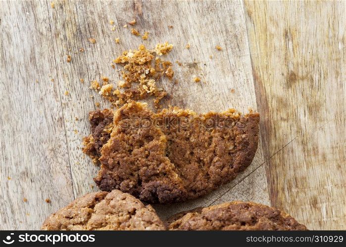 scattered on the wooden floor and sprinkling crumbs round-shaped oatmeal cookies during breakfast or dessert meal. crumbs round-shaped oatmeal cookies