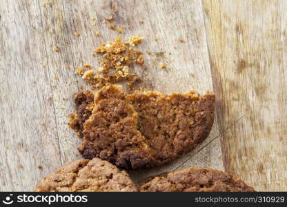 scattered on the wooden floor and sprinkling crumbs round-shaped oatmeal cookies during breakfast or dessert meal. crumbs round-shaped oatmeal cookies