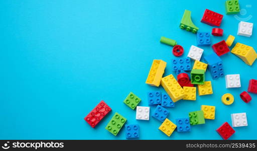 Scattered parts of a plastic children&rsquo;s designer, top view. Yellow blue background, copy space