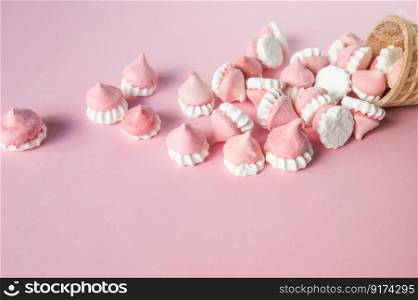 Scattered pink and white decor for baking, meringue in waffle cookies. Multicolored pink and white meringues in waffle cookies lie scattered on a pink background