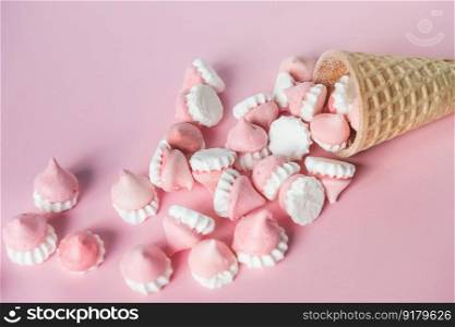 Scattered pink and white decor for baking, meringue in waffle cookies. Multicolored pink and white meringues in waffle cookies lie on a pink background