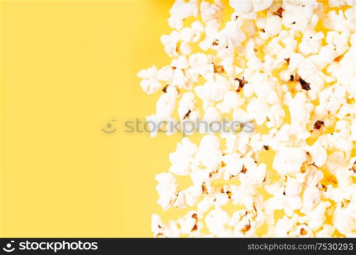 Scattered popcorn border over plain yellow desk background. Scattered popcorn over yellow background