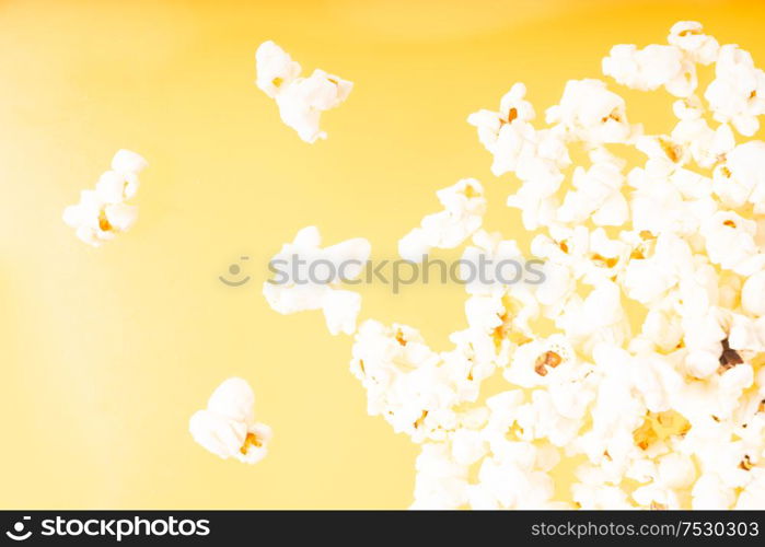 Scattered popcorn over yellow background, close up top view. Scattered popcorn over yellow background