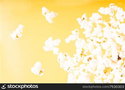 Scattered popcorn over yellow background, close up top view. Scattered popcorn over yellow background