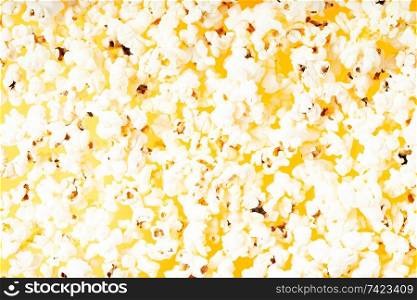 Scattered salted popcorn food textured background.. Scattered popcorn over yellow background