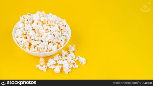 Scattered tasty cheese popcorn in bowl isolated on yellow background. Wallpaper, banner, header with copy space for text