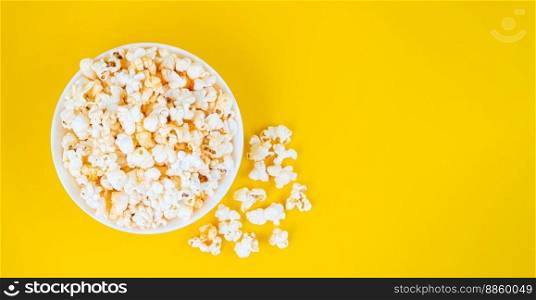 Scattered tasty cheese popcorn in bowl isolated on yellow background. Wallpaper, banner, header with copy space for text