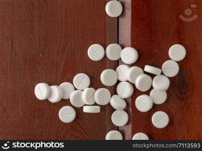scattered white round tablets on a dark wooden table