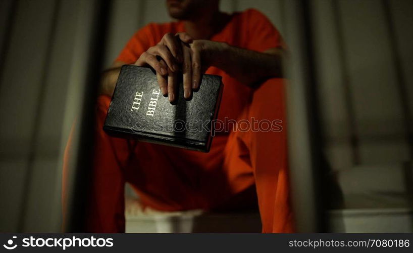 Scene of an inmate holding a bible in prison