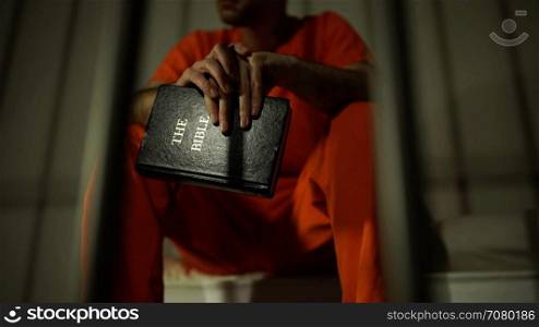 Scene of an inmate holding a bible in prison