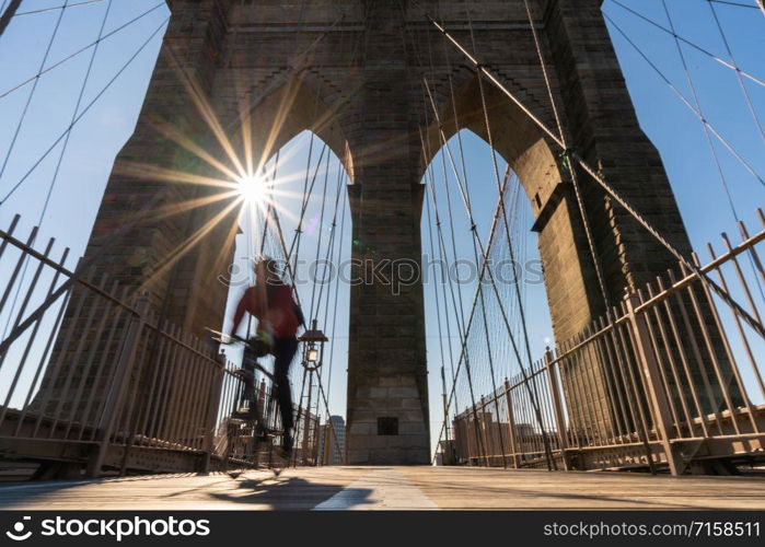 Scene of stop motion bicycle with Brooklyn bridge when sunrise, USA downtown skyline, Architecture and building with tourist concept