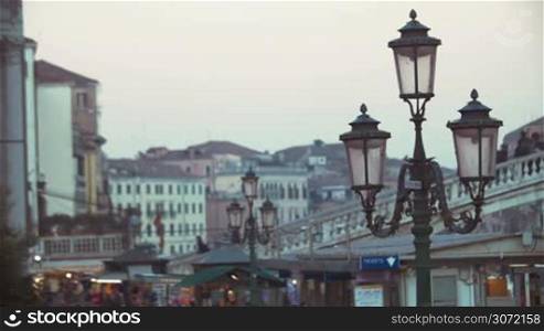 Scene of Venice, Italy. Vintage lantern in foreground, buildings, people going up and down the bridge in background