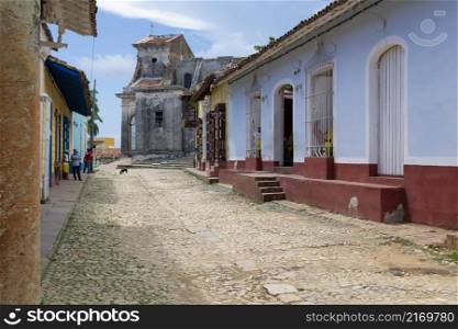 Scene on the street with colorful houses and background old church in the center of Trinidad, Cuba.