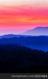 Scenery of blue mountains against colourful sunrise sky, abstract ripples clouds in the early light. Holiday, vacations concepts. Soft focus on the sky.