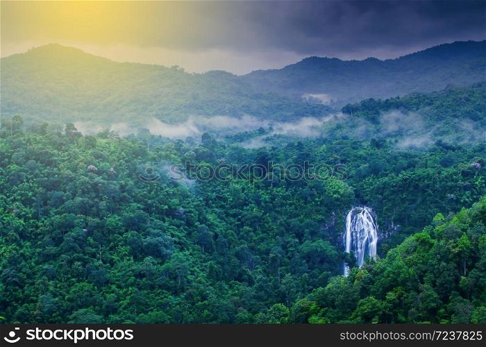 Scenery of tropical waterfall in the morning mist, stunning aerial view of waterfall in a tropical rainforest at sunrise. Khlong Lan National Park, Thailand. Long exposure.