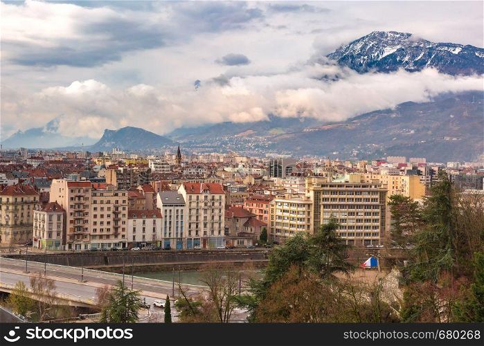 Scenic aerial view of the banks of the Isere river, bridge, roofs and French Alps on the background, Grenoble, France. Old Town of Grenoble, France