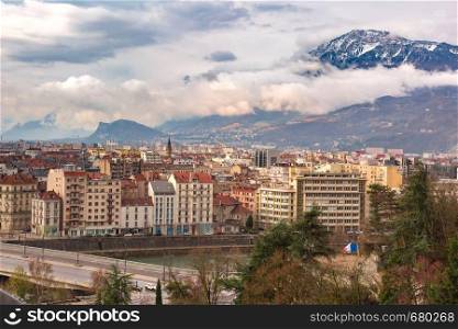 Scenic aerial view of the banks of the Isere river, bridge, roofs and French Alps on the background, Grenoble, France. Old Town of Grenoble, France