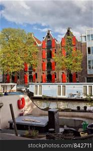 Scenic canal in Amsterdam with boats and apartment house, former warehouse building, Netherlands, North Holland.