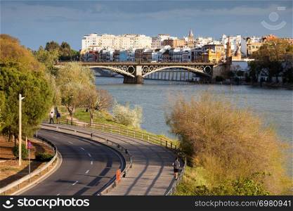 Scenic city of Seville in Andalusia, Spain. Guadalquivir river waterfront, Isabel II Bridge and Triana district in the background.