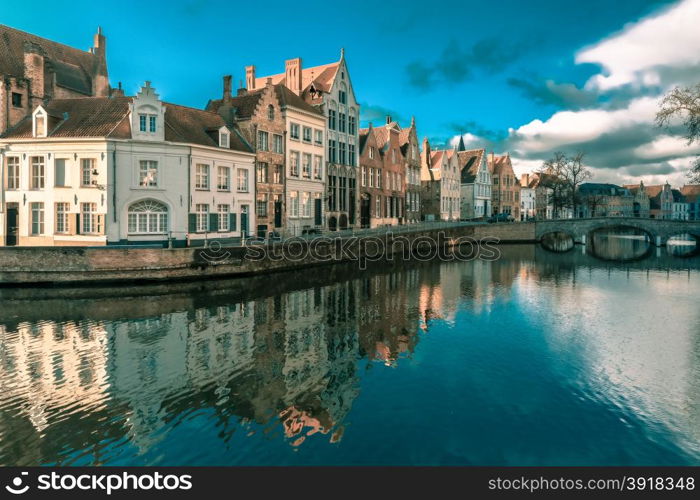 Scenic city view of Bruges canal Spiegelrei with beautiful medieval houses, their reflections and Bridge Carmersbrug, Belgium. Toning in cool tones