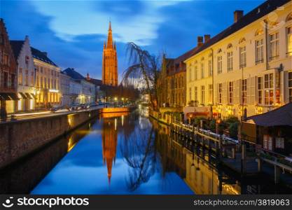 Scenic cityscape with a medieval fairytale canal and the quay Dijver and Church of Our Lady at sunset in Bruges, Belgium
