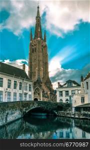 Scenic cityscape with a medieval fairytale canal and the quay Dijver and Church of Our Lady in Bruges, Belgium. Toning in cool tones