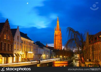 Scenic cityscape with a medieval fairytale canal and the quay Dijver and Church of Our Lady at Moonlight in Bruges, Belgium