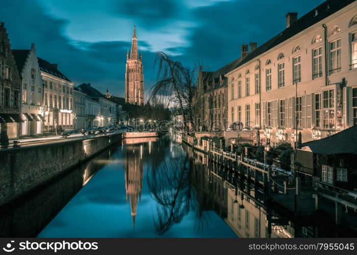 Scenic cityscape with a medieval fairytale canal and the quay Dijver and Church of Our Lady at sunset in Bruges, Belgium. Toning in cool tones