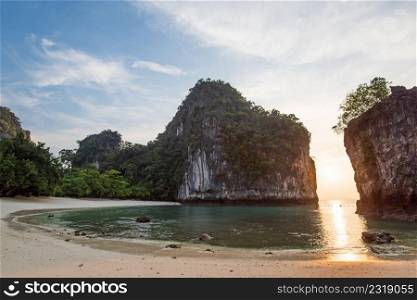 Scenic curve of tropical beach in morning light, sunrise shines through fantastic cliff on blue sea and white sand beach. Summer season. Koh Hong Island, Andaman sea, Krabi, Thailand. Summer season. Copy space.