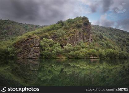 Scenic landscape of reflections and ruins in a tranquil lake on a cloudy day, La Rioja, Spain.
