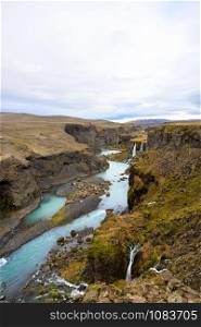 Scenic landscape view of incredible Sigoldugljufur canyon in highlands with turquoise river, Iceland. Volcanic landscape on background. Popular tourist attraction.