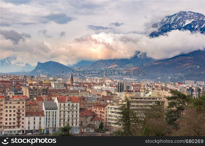 Scenic panoramic aerial view of the banks of the Isere river, bridge, roofs and French Alps on the background, Grenoble, France. Panorama Old Town of Grenoble, France