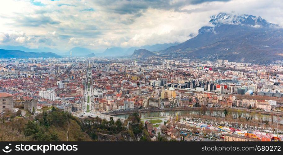 Scenic panoramic aerial view of the banks of the Isere river, bridge, roofs and French Alps on the background, Grenoble, France. Panorama Old Town of Grenoble, France