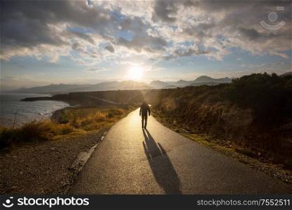 Scenic road in the mountains. Travel background. Man going on sunrise background.
