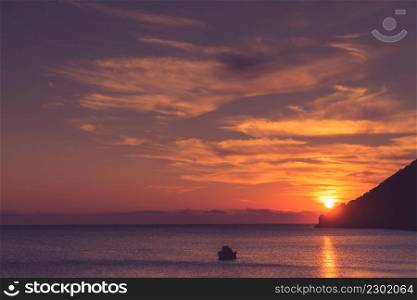 Scenic sunrise or sunset over sea surface, boat anchored in bay, Greece. Sunrise or sunset over sea surface