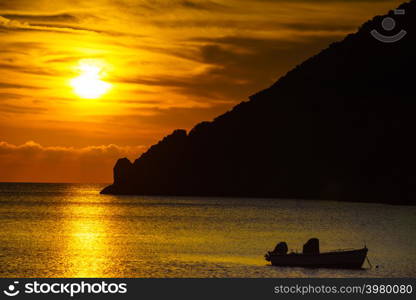 Scenic sunrise or sunset over sea surface, boat anchored in bay, Greece. Sunrise or sunset over sea surface