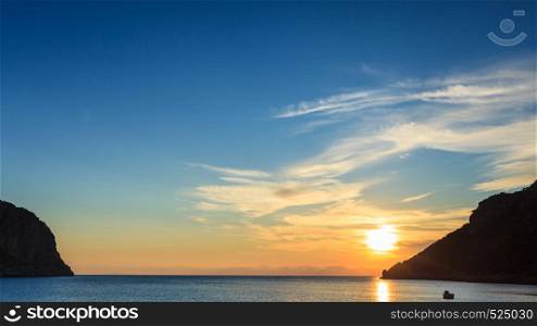 Scenic sunrise or sunset over sea surface, boat anchored in bay, Greece. Sunrise or sunset over sea surface