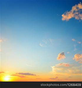 Scenic sunset with sun rays against bright blue sky and orange clouds