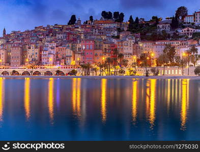 Scenic view of colorful medieval houses in the historical part of the city at sunset. Menton. France.. Menton. Antique multi-colored facades of medieval houses on the shore of the bay.