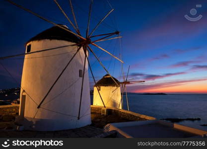Scenic view of famous Mykonos Chora town windmills. Traditional greek windmills on Mykonos island illuminated in the evening, Cyclades, Greece. Walking with steadycam.. Traditional greek windmills on Mykonos island at sunrise, Cyclades, Greece