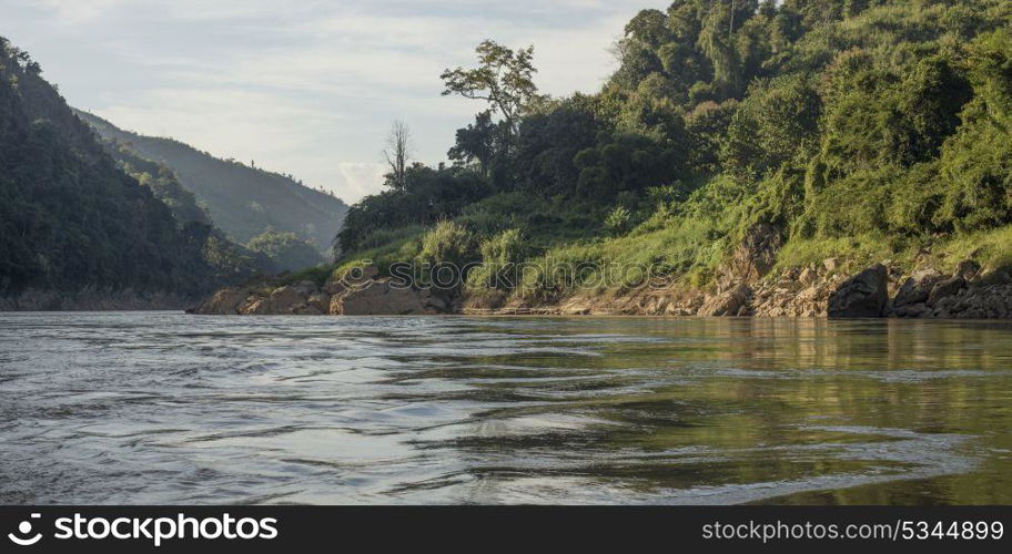 Scenic view of river shoreline with mountain range in background, River Mekong, Sainyabuli Province, Laos