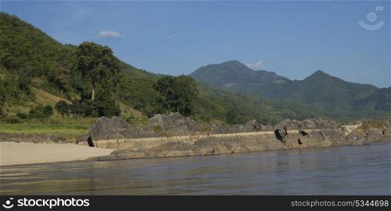Scenic view of riverbank with mountain range in background, River Mekong, Sainyabuli Province, Laos