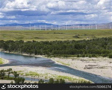Scenic view of stream with wind turbines in background on rural landscape, Southern Alberta, Alberta, Canada