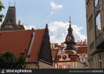 Scenic view of the historical center of Prague: houses, buildings, palaces, landmarks of old town with the characteristic and picturesque red rooftops and multi-coloured walls. Carpenters working on rooftop